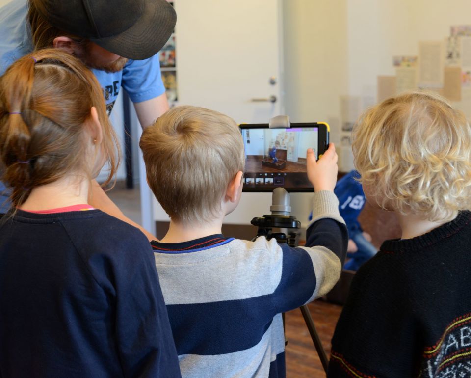 Børn og voksen arbejder med stop motion ved tablet på stativ.